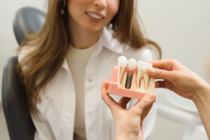 Dental Patient Getting Shown A Dental Implant Model During Her Consultation in Cedarhurst, NY