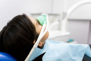 Woman receiving nitrous oxide sedation at dental clinic during treatment.